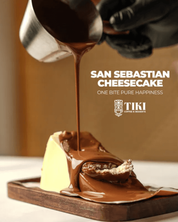 Sliced San Sebastian burnt cheesecake with a dark chocolate pour on a walnut board